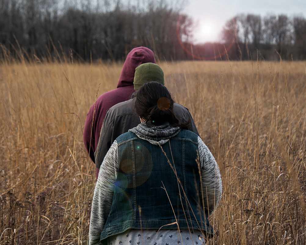 Fall Destinations: a group of three hike through a field.